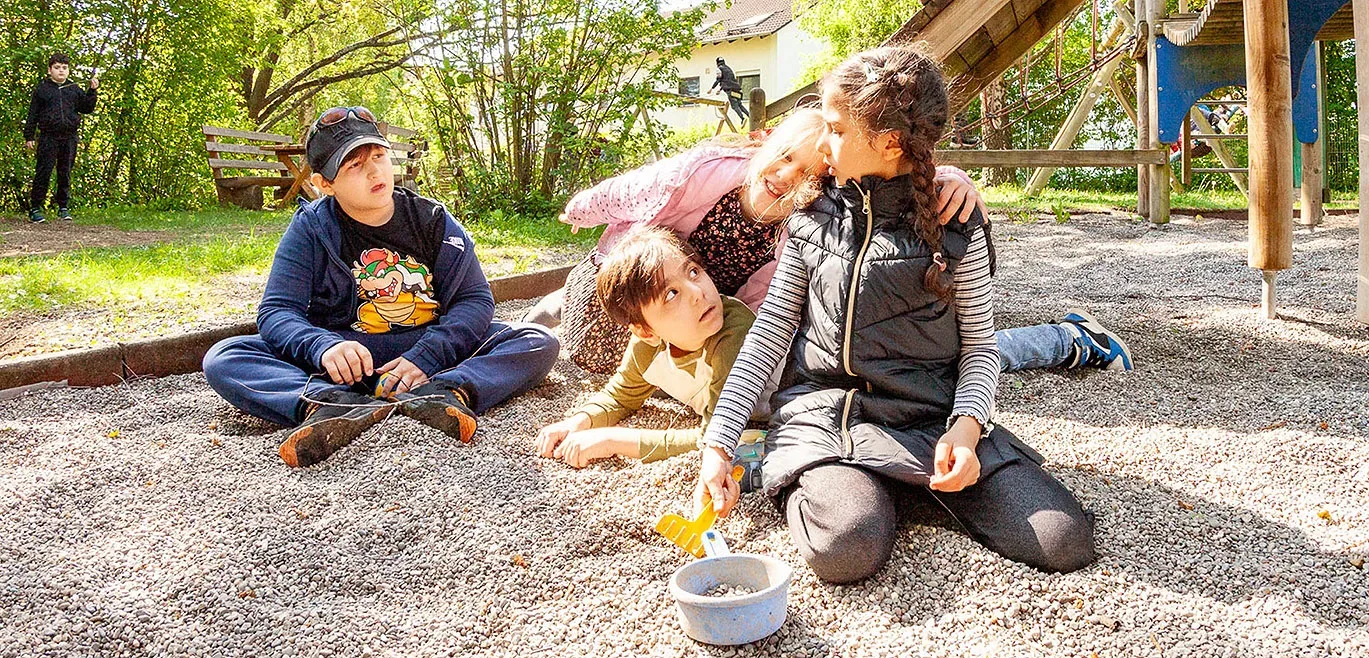 4 Schüler sitzen im Sandkasten